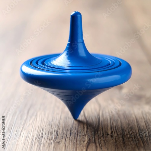 A blue spinning top rests on a wood surface