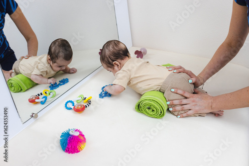 Foto Physiotherapist encourages baby to spend time on their tummy to help develop head, neck, and upper body strength