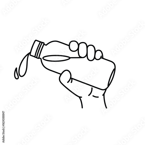 Hand pouring liquid from a bottle with drops falling