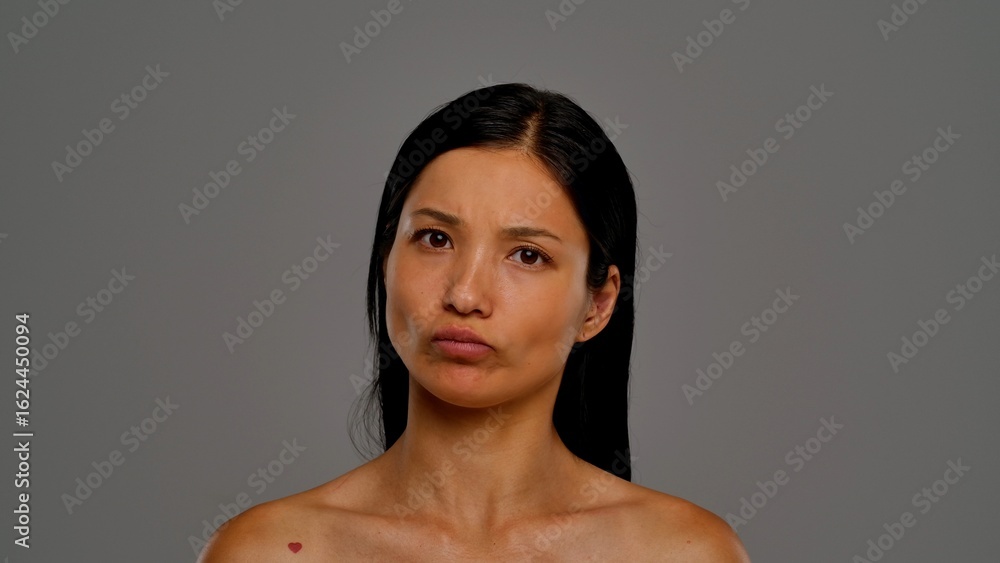 Obraz premium Woman Making a Puzzled Face Expression Against Neutral Background
