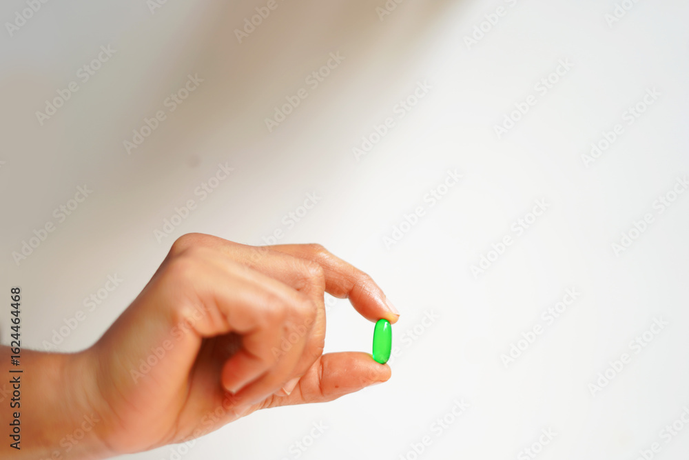 Fototapeta premium hand with a Vitamin E capsule 