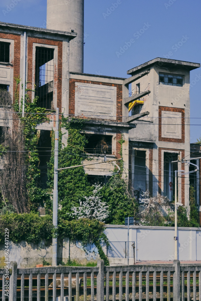 Obraz premium Abandoned Industrial Chimney Tower with Overgrown Vegetation
