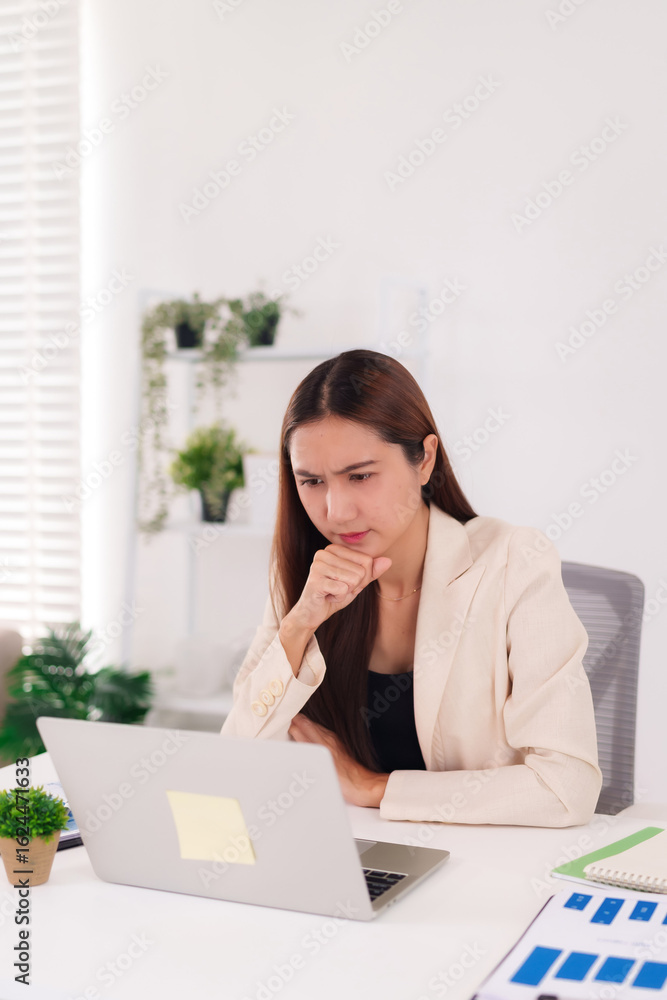 Asian adult businesswoman analyzing financial data charts on laptop at modern office desk problem solving business strategy Asian adult businesswoman analyzing financial data charts on laptop at modern office desk problem solving business strategy