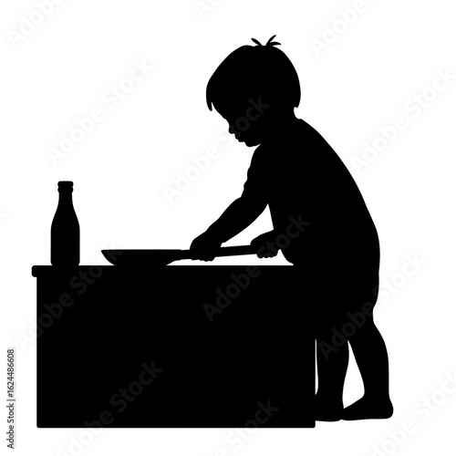Silhouetted figure of little child near kitchen counter preparing pancakes with bottle. Silhouetted cooking image with little chef preparing dish with cooking pan, pancakes and bottle on table.