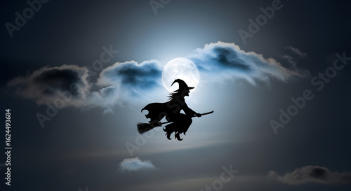 Silhouette of a witch on a broomstick silhouetted against the moonlight in the night sky