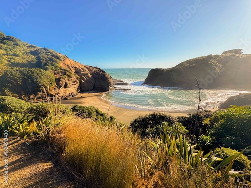 Vast wide beautiful blue ocean with giant rocks and sandy beach in New Zealand