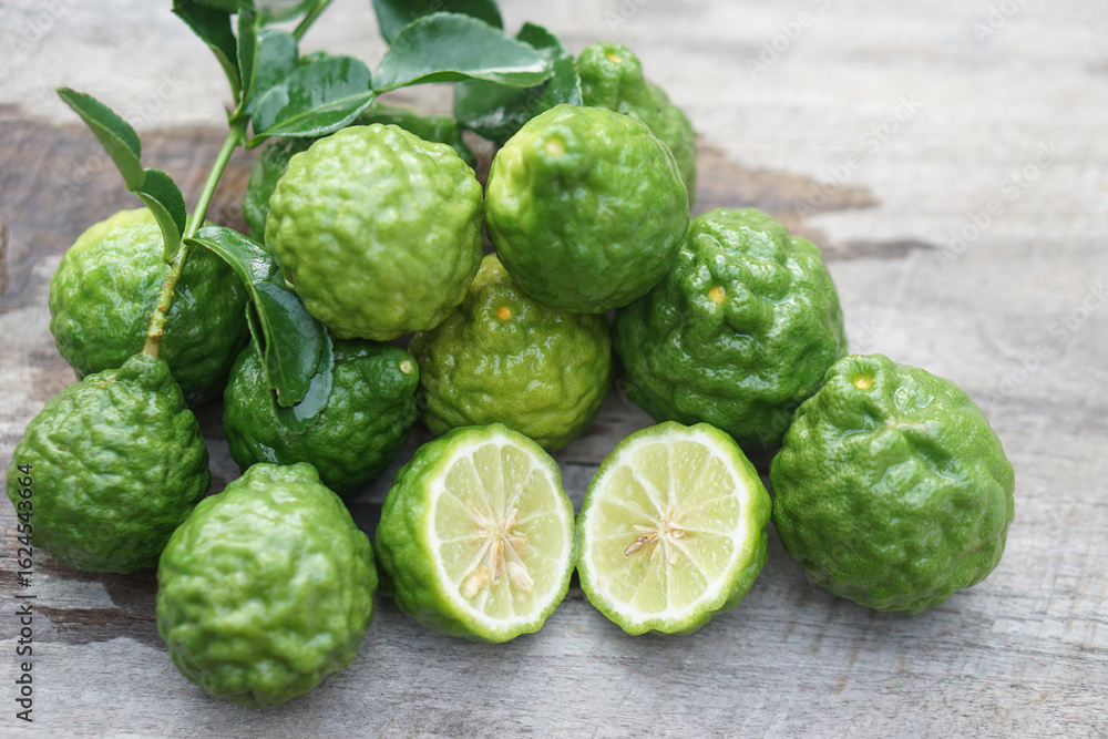 Fototapeta premium Fresh kaffir limes fruits. Aromatic Thai herb is used for cooking with sour taste, natural shampoo and homemade cleaners. Known for its citrusy fragrance and traditional medicinal properties. 