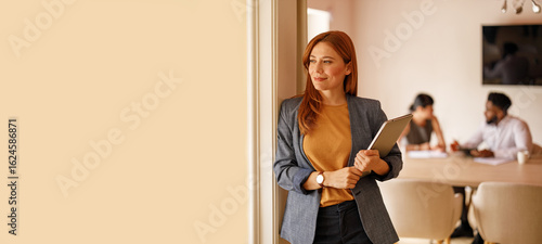 Foto Thoughtful businesswoman with laptop looking away confidently while leaning on w