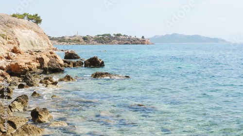 Wallpaper Mural Sunny day at the rocky coastline of Aegina, Greece. Clear turquoise sea, stone cliffs, distant island and calm waves. No people, natural landscape, Greek island scenery. Torontodigital.ca