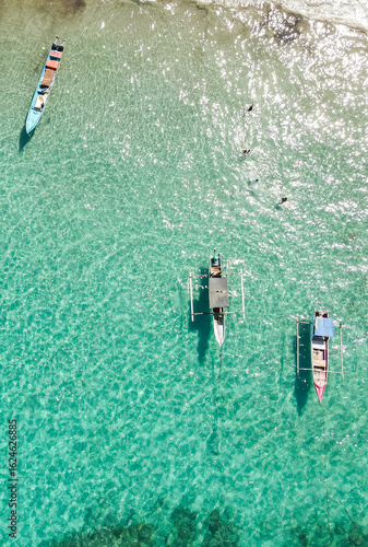 The beauty of traditional wooden fishing boats floating on clear turquoise waters seen from above. Located in Atauro, Timor Leste.