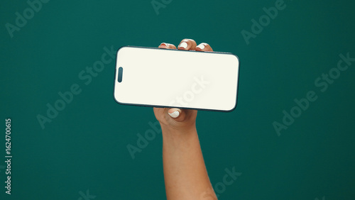 Hands, woman and phone screen with mockup in studio for digital marketing, advertising space or UX. Mobile user, person and smartphone display on green background for coming soon deal and promotion