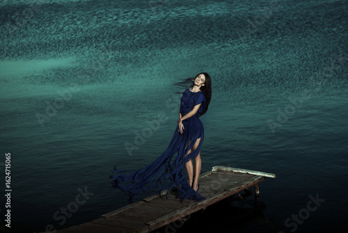 Enchanting Model in a Flowing Dress Posing Gracefully Against Serene Waters and Nature
