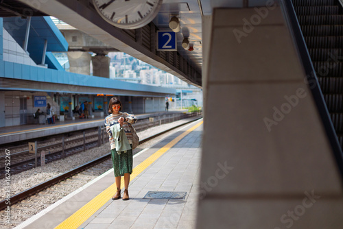 girl looking at watch. girl standing at train station waiting for train. woman with backpack waiting for train.