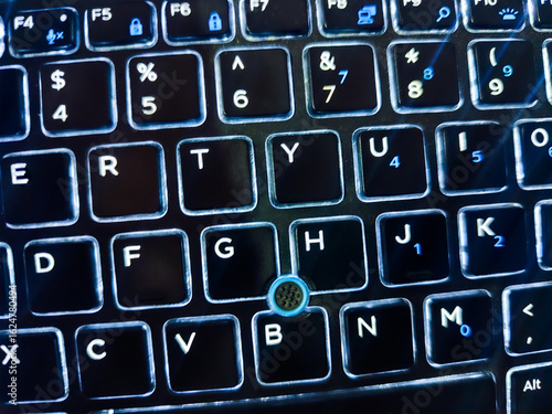 Backlit laptop keyboard with glowing illuminated keys in the dark