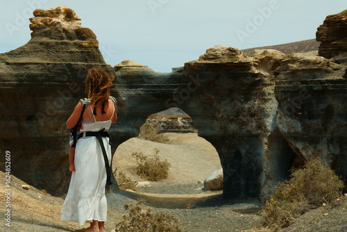 Mujer con niño frente a formaciones rocosas en la antigua rofera de Lanzarote, Islas Canarias