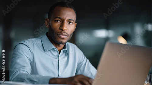 Focused Vision: A determined individual is immersed in his work environment. Using a laptop to get the job done, in a modern interior design setting. Capturing professionalism and business atmosphere.