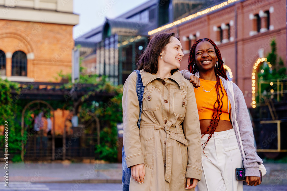 Fototapeta premium Diverse friends walk together talking and smiling after rain