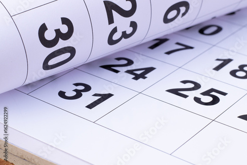 Paper rolled on the wooden table pointing number 30 in the calendar