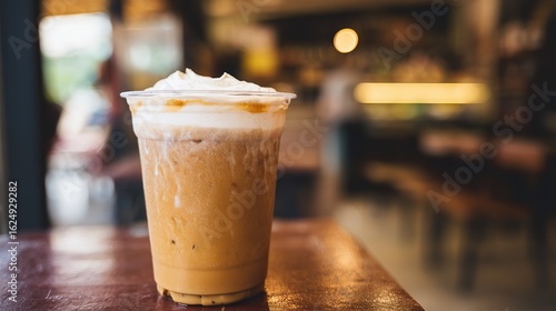 An iced coffee drink served in a clear plastic cup on the coffee table. Refreshing cold drinks, creamy iced coffee, café setting, summer drinks, and casual café moment concepts.