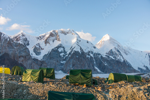 Tableau sur toile A line of green mountaineering tents on a rocky landscape with majestic snowcapp