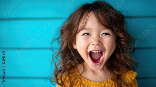 A joyful child with curly hair laughs exuberantly, embodying pure happiness against a bright blue background, capturing the essence of childhood delight and innocence.