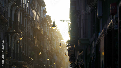 The light of the sun at dawn on the street lamps of a Pamplona street at the beginning of the fourth stage of the Camino de Santiago

