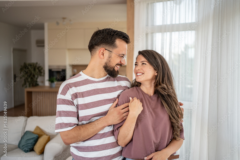 Happy couple embracing and smiling in modern living room Happy couple embracing and smiling in modern living room