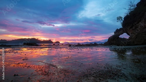 Beautiful sunset over the sea with rock formation and reflection on the beach