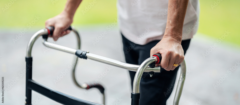 Obraz premium Elderly hands gripping walker for secure movement during daily stroll outdoors enhancing personal independence