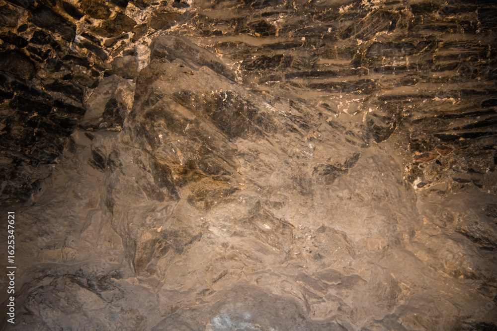 Fototapeta premium Natural rock formation with textured patterns in warm underground lighting