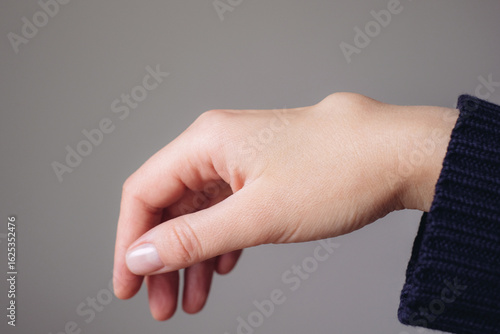 Female right back hand with ganglion cyst on the dorsum,  fluid-filled bump associated with a joint or tendon sheath, close-up view, selected focus.
