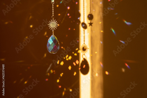 Glass suncatcher with metal golden chains, shining in sunlight and reflecting the rainbow on a yellow background