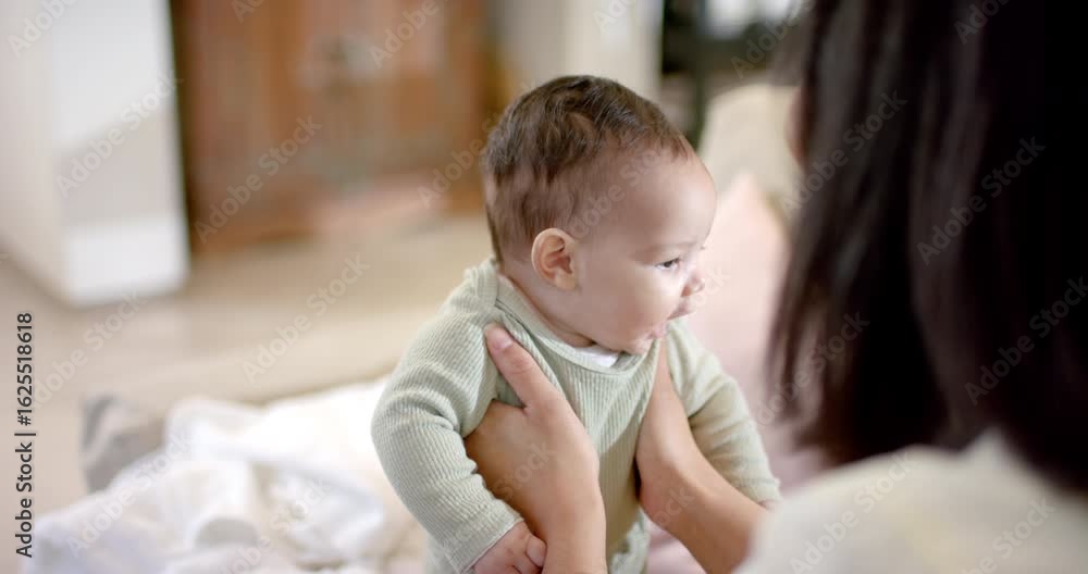 Mother noticing daughter gaze and lifting her to sit on blanket, guiding head turns in bedroom Mother noticing daughter gaze and lifting her to sit on blanket, guiding head turns in bedroom