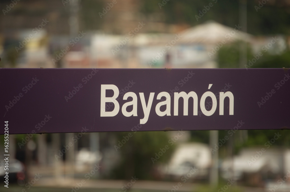 Fototapeta premium Letrero con la palabra “Bayamón” en una estación del Tren Urbano en Bayamón, Puerto Rico. La imagen destaca el sistema de transporte público y la identidad urbana de la ciudad.