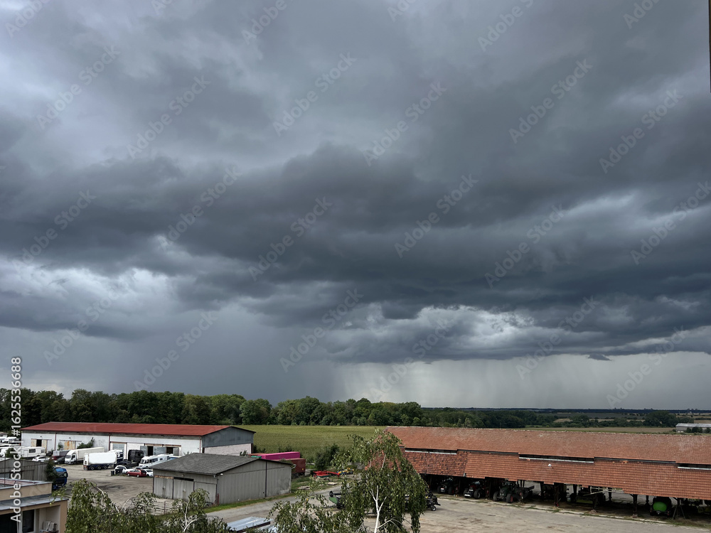 Storm clouds over the landscape. View of an agricultural environment with garages and fields. Storm clouds over the landscape. View of an agricultural environment with garages and fields.