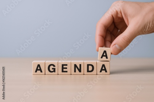 Hand Places Letter A on Wooden Blocks Spelling Agenda, Business Meeting Concept
