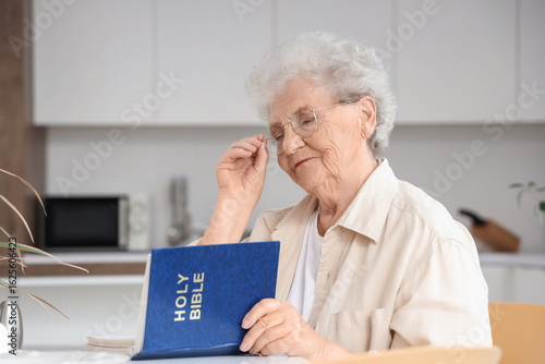 Senior woman reading Bible ...