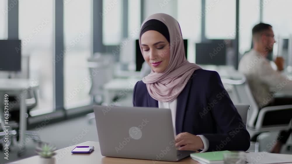 Smiling Muslim Woman Working on Laptop in Modern Office. Smiling Muslim Woman Working on Laptop in Modern Office.