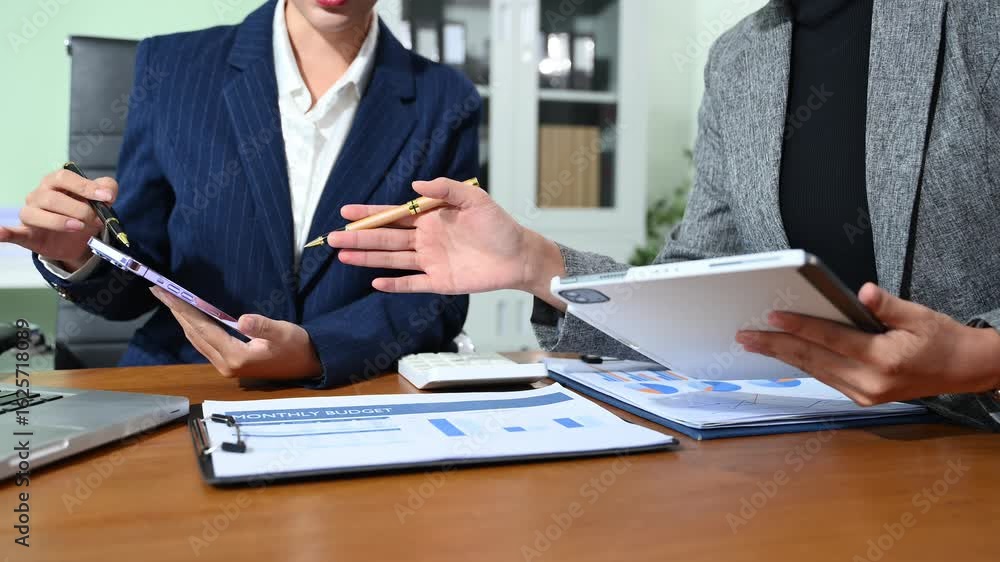 Business documents on office table with smart phone and calculator digital tablet and graph business with social network diagram and two colleagues discussing data Business documents on office table with smart phone and calculator digital tablet and graph business with social network diagram and two colleagues discussing data
