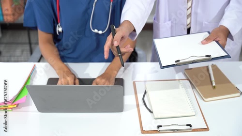 Healthcare Professionals' Collaboration: Focused view of a physician and nurse working together, reviewing a chart on a laptop. Illustrating teamwork and the complexities of medical care. 