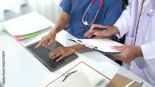 Doctors Consultation: Two medical professionals collaborating on a laptop at a desk, reviewing patient records, symbolizing dedication to healthcare