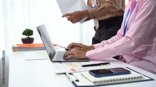 Teamwork and Technological Harmony: colleagues collaborating on work tasks, focusing on the laptop, and engaged in project discussion in a bright office setting.