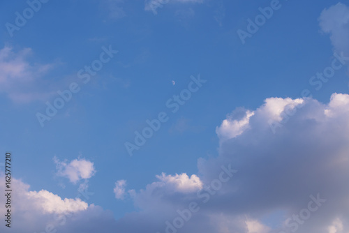 Slika na platnu Dramatic sky with blue tones, fluffy white clouds, dark storm clouds, and a visible daytime moon