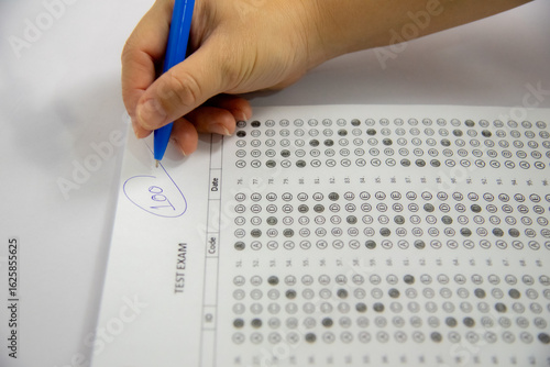 shows a hand holding a blue pen and writing the number 