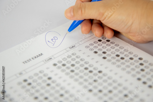 shows a hand holding a blue pen and writing the number 