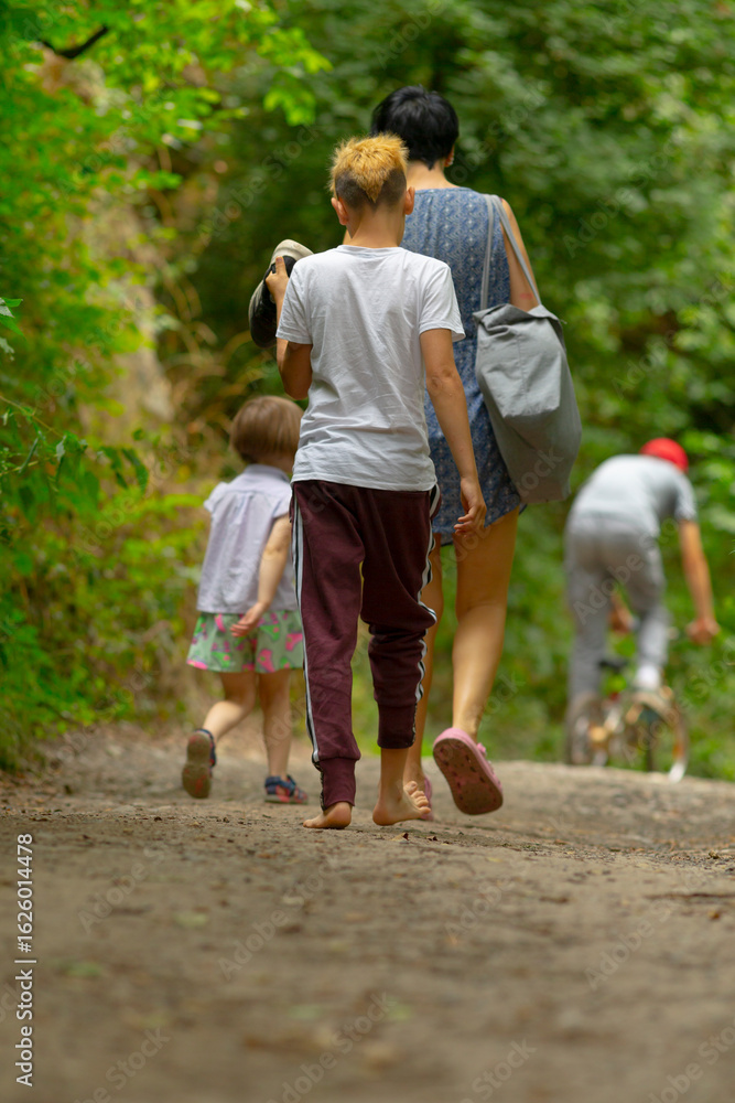 Fototapeta premium A group of diverse individuals are casually walking down a narrow dirt path deep within the peaceful woods surrounded by nature