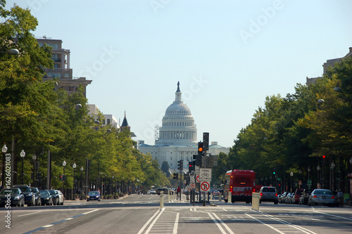 View down Pennsylvania Avenue in Washington, D.C., with the U.S. Capitol building framed by trees and traffic under a clear sky