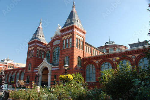 The Smithsonian Castle in Washington, D.C., with its iconic red sandstone facade and garden foreground under a clear blue sky