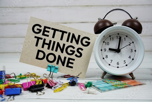 Quadro su tela Getting Things Done text on paper card with alarm clock and stationary on wooden