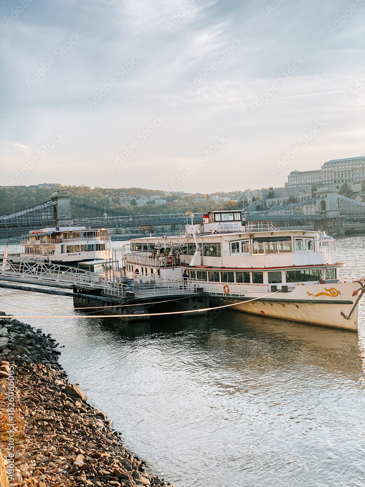 Fototapeta premium Beautiful riverboats docked along the scenic waterfront in Budapest during golden hour